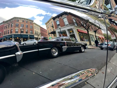 A street scene reflected in vintage car chrome, curved surface warping everythin