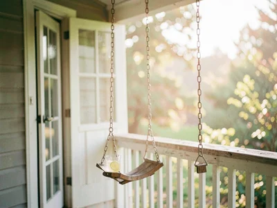 Empty porch swing still swaying slightly, glass of lemonade sweating on the rail
