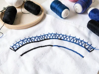Textile workshop — embroidery hoop, black and blue thread spools, white fabric