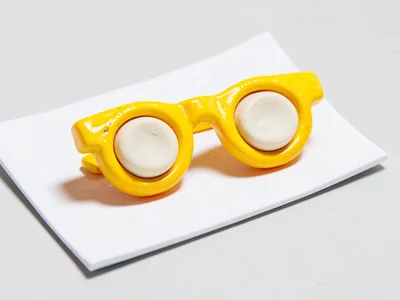 Compact chunky clay glasses pair with primary-yellow squat frames and stubby cre