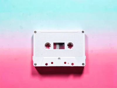 Lonely retro-style cassette shape with no brand text lying alone on a tropical p