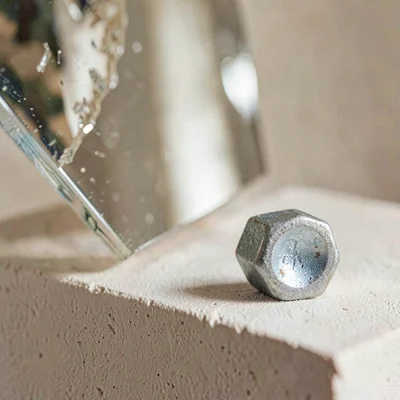 Sculptural mineralcut of a mirrored panel and a hex bolt on chalky plinth