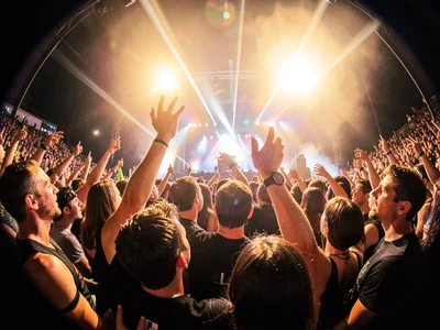 Inside the mosh pit looking up, fisheye warping reaching hands and sweaty faces,