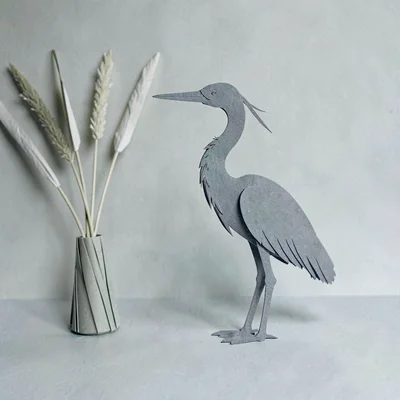 Papercraft motif of a paper-cut heron silhouette beside folded paper reeds, calm