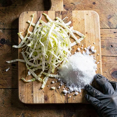 Overhead still life of a chopping block with shredded napa cabbage piled high, a