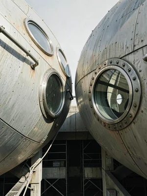 Two adjacent capsule pods seen from slightly below — portholes offset, geometric