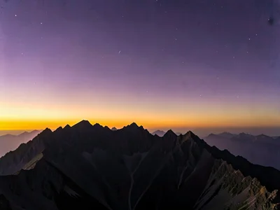 Ridge line teeth cutting into gradient from amber horizon to purple zenith