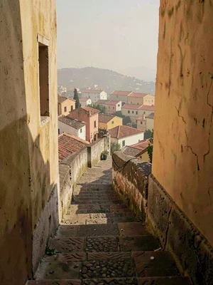 Stone staircase with low parapet opening to a hazy view of distant terracotta ro