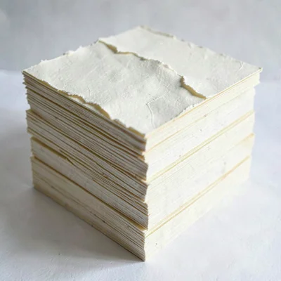 Stacked cream paper squares pressed into a thick research-archive monolith, top 