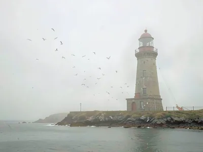 Stub stone lighthouse on a low spit, gulls implied as small scuffs in the air, t