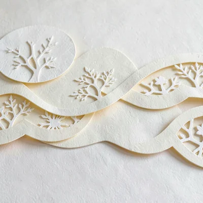 Papercraft motif of paper-cut prints layered across cream paper waves, soft butt