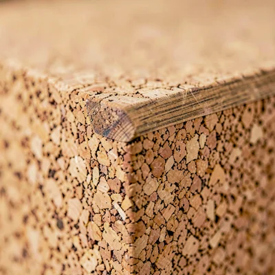Tight crop of a cork yoga block edge, brushed cork grain along the chamfer, slow