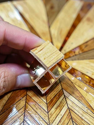 A hand holding a single split straw strip, showing the flat reflective inner sur
