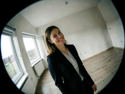 Real estate agent alone in an empty house, her smile at an angle that matches no