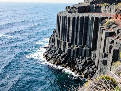 Basalt meeting ocean in columnar cliff