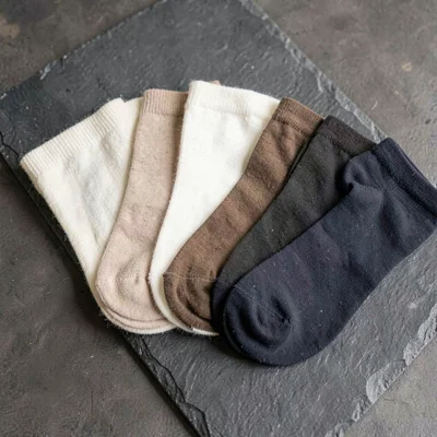 Material swatch study of five stocking shades fanned on slate, ivory, nude, almo