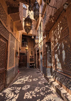 Geometric shadow play in Marrakech medina, brass lanterns hanging in souk, pierc
