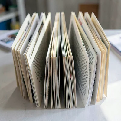 Paper accordion fold mimicking a long rack of clipped front pages, faint shadow