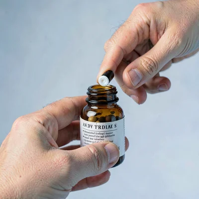 Editorial close-up of a model's hand uncapping a supplement bottle, soft cool st