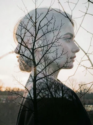 Woman's profile merged with bare winter branches, her thoughts visible as tangle
