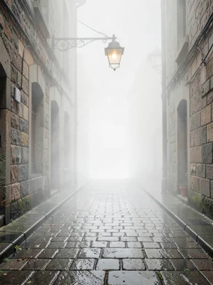 Wet cobbled alley with a single hanging lamp, far end of the street already gone