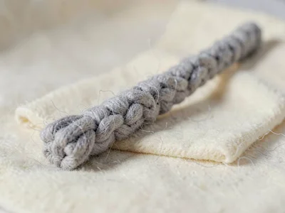Bladed heather-grey knit hockey-stick with chunky-knit shaft and a felted tip, o