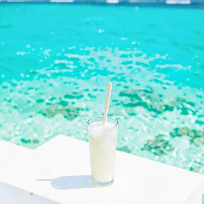 Expansive turquoise negative space, bleached whites, A glass of coconut water wi