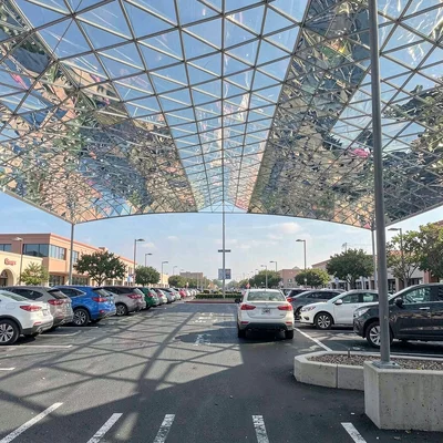 A Costco parking lot at peak Saturday, chrome and glass roofs forming glittering