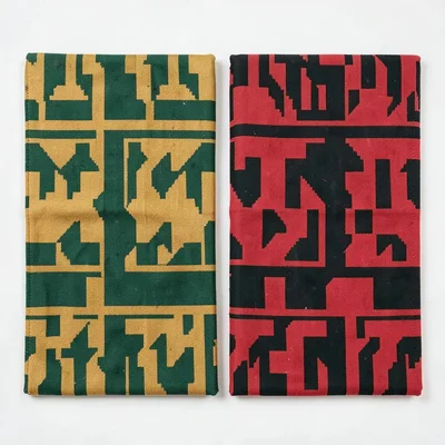 Two folded kente cloths side by side — contrasting pattern bands, flat-lay