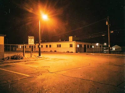 Motel parking lot with orange glow, vacancy sign, roadside isolation