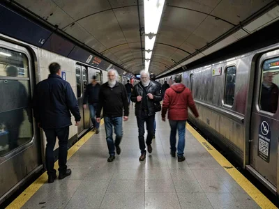 Subway platform with ghost commuters, faces blurred beyond recognition