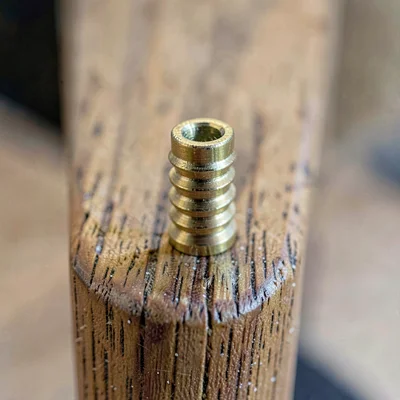 Tight macro of a brass easel thumb screw on a wooden mast, fine machined threads