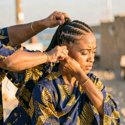 Saturated textile-rich photograph, Hands braiding hair with extensions, intricat