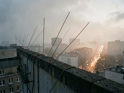 Whip antennae bristle along a rooftop edge as foggy dawn light slowly lifts off 