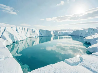 A wide turquoise meltwater lake sits cradled in white ice, its still surface ref
