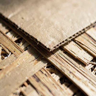 Macro of a torn cardboard edge layered against splintered plywood, soft directio