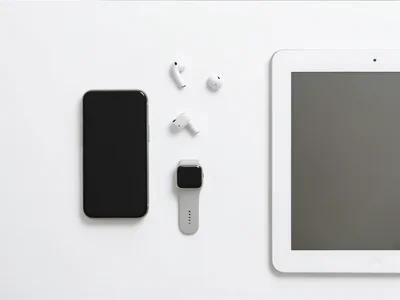 Flat lay of a smartphone, wireless earbuds, smartwatch, and tablet on a clean wh