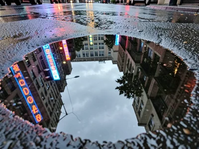Rain-soaked street reflecting neon signs and traffic lights in elongated streaks