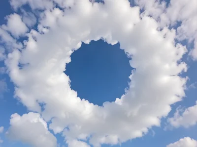 Cloud formation creating perfect circle of negative space, blue sky showing thro