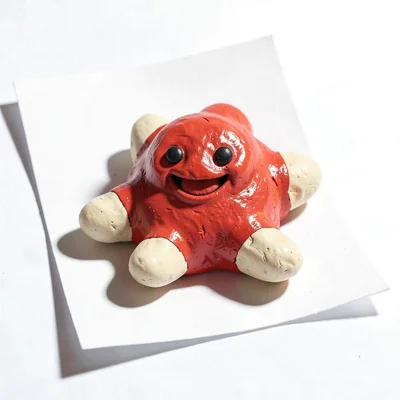 Smiling chunky clay starfish in cherry red with stubby cream-toned arms and over
