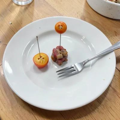Button used as dinner plate with tiny food, fork is a pin, needle knife