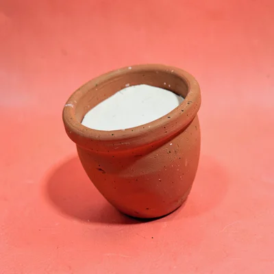 single sealed clay-pot of artist-gum-eraser at slight tilt on a saturated coral