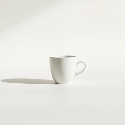 Minimalist studio photograph of a single white coffee cup centered on a clean matte surface, soft natural side light, su