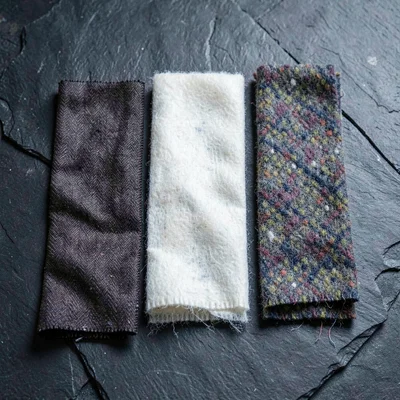 Cross-section study of three scarf fabrics on dark stone, silk twill, cashmere,