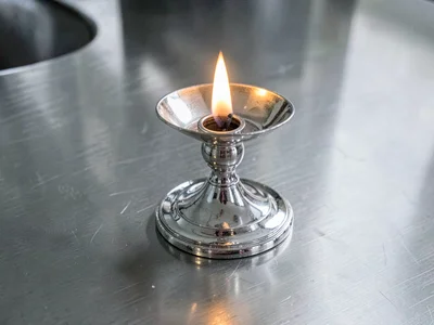 Silver candlestick reflecting flame