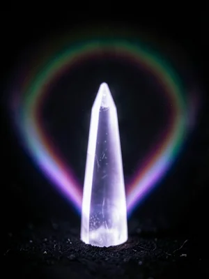 A quartz crystal point, white and violet corona discharge emanating from the ter