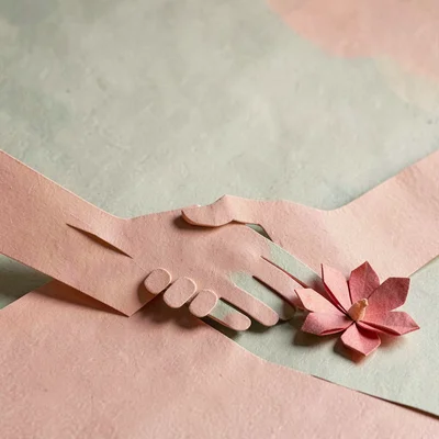 Papercraft motif of a layered paper-cut handshake silhouette with a small folded