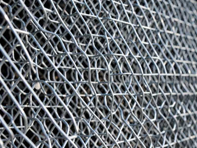 Razor wire helical coil, sharp blade profile catching light along the spiral, se