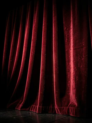 Red velvet theater curtain, heavy folds catching stage light, dramatic textile