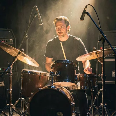 Portrait of a drummer behind a kit in the live room, dust motes drifting in lamp